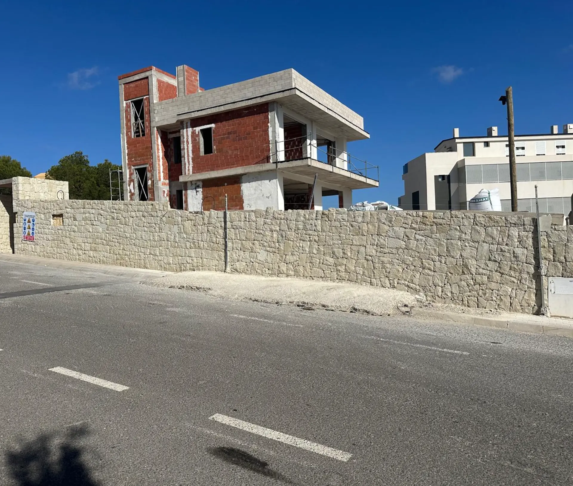 Villa under construction behind a natural stone boundary wall
